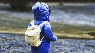 Kind mit Rucksack und Regenjacke