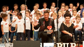 Hartmut Engler mit Herzenssache-Kids auf der Bühne