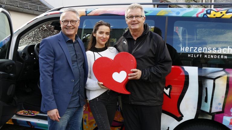 Emilija Wellrock und Sparda-Bank Vorsitzender Manfred Stang bei der Übergabe des Herzenssache-Busses