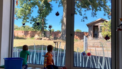 Kinder schauen vom Kinderhaus nach draußen