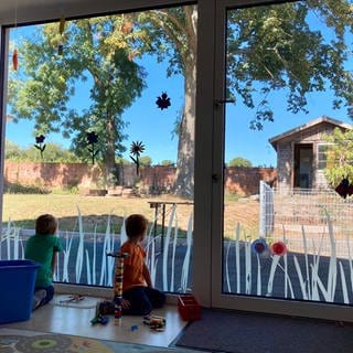 Kinder schauen vom Kinderhaus nach draußen