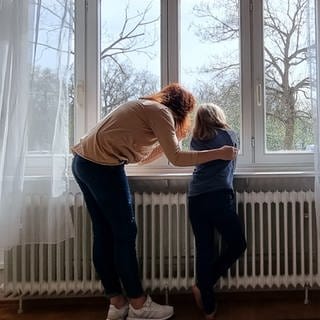 Mädchen und junge Frau schauen aus einem Fenster - nachgestellte Therapieszene