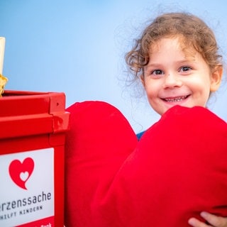 Mädchen hält rotes Herz in der Hand und schaut verträumt