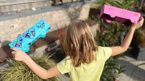 Herzenssache-Projekt Löwenzahn Mädchen (von hinten zu sehen) spielt mit zwei Papierautos