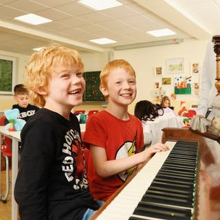 Lachende Jungen am Klavier