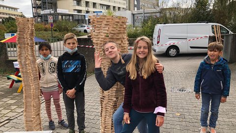 Kinder spielen vor zwei großen Türmen aus Bauklötzen.