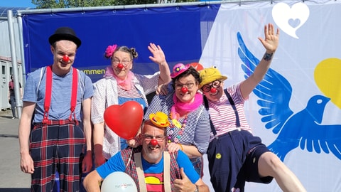 Die Clowns von true!moments vor einer Wand mit ukrainischer Friedenstaube