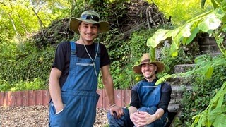 Zwei Jugendliche in blauen Arbeitshosen lachen in die Kamera